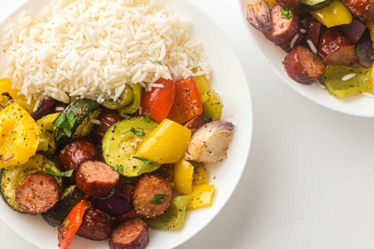 Sheet pan sausage and roasted vegetables served with white rice and fresh herbs.