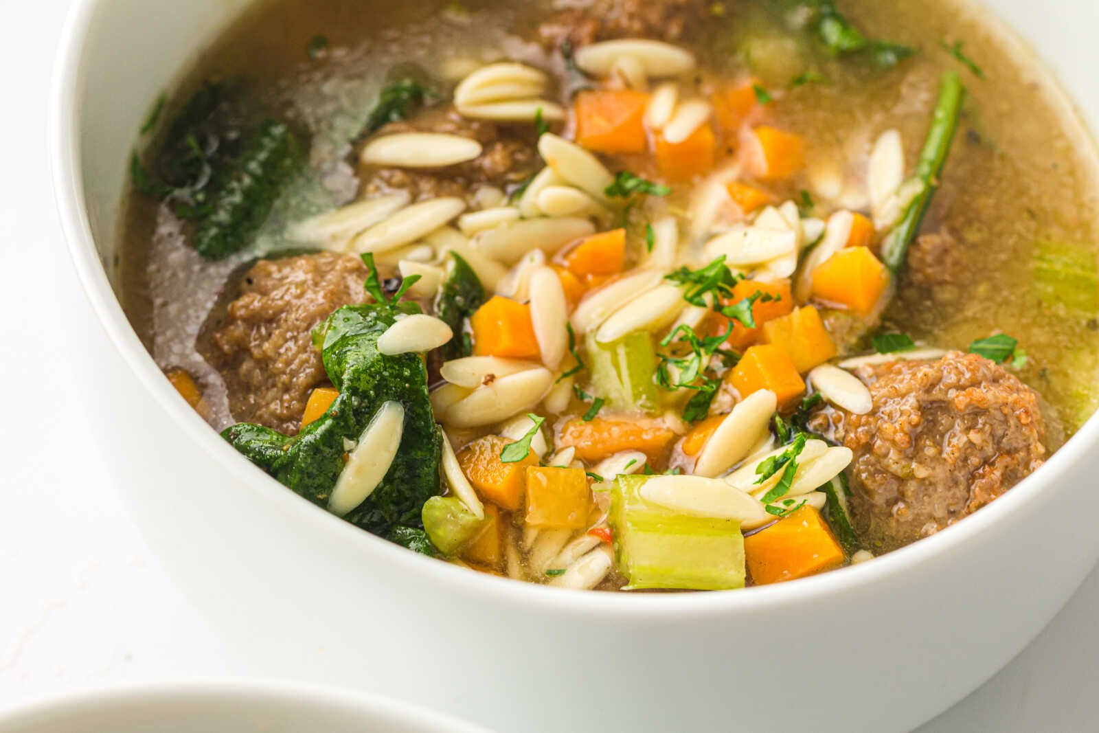 Bowl of slow cooker Italian wedding soup with meatballs, orzo, spinach, and vegetables