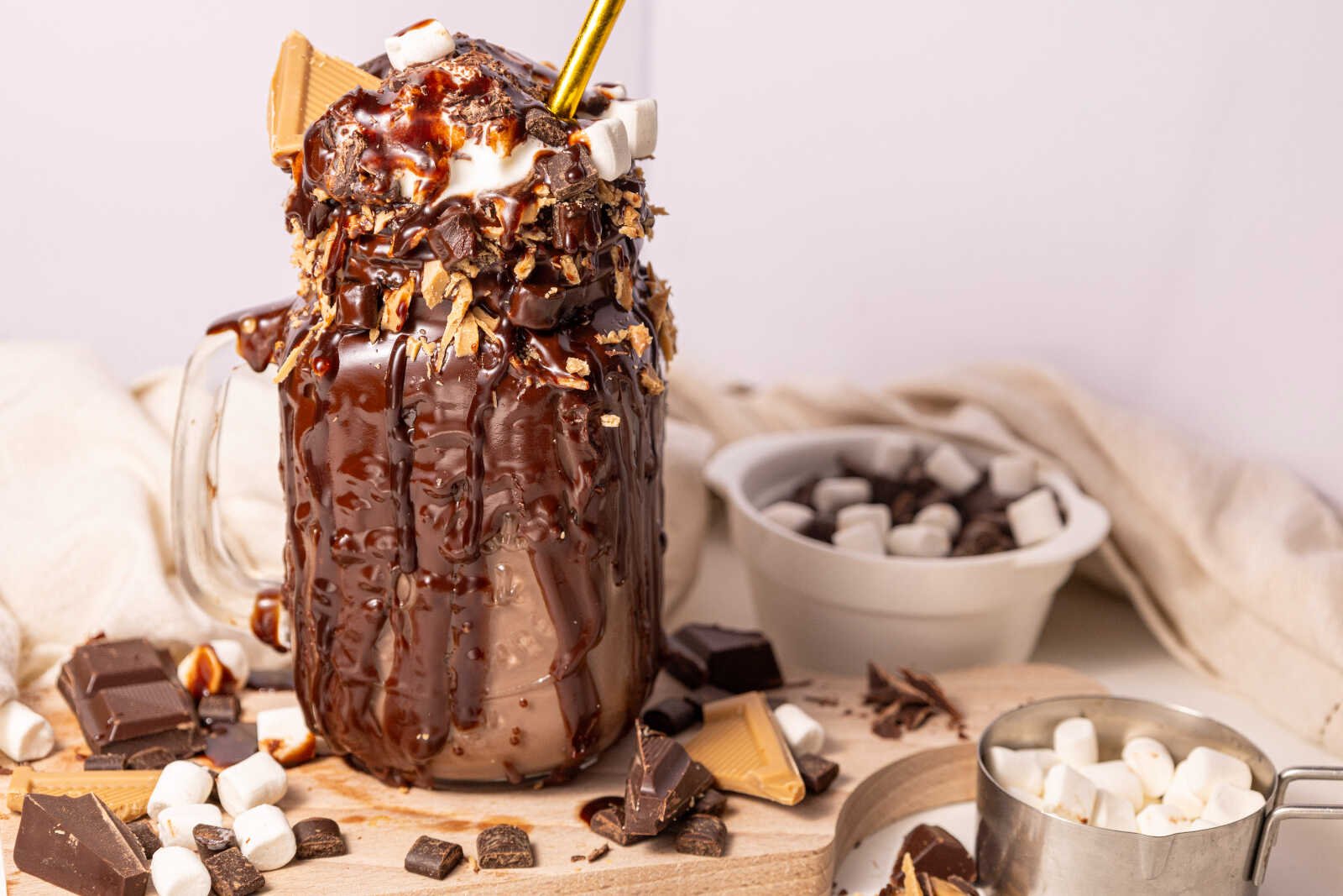 Chocolate freakshake with whipped cream, marshmallows, and chocolate drizzle in a mason jar.