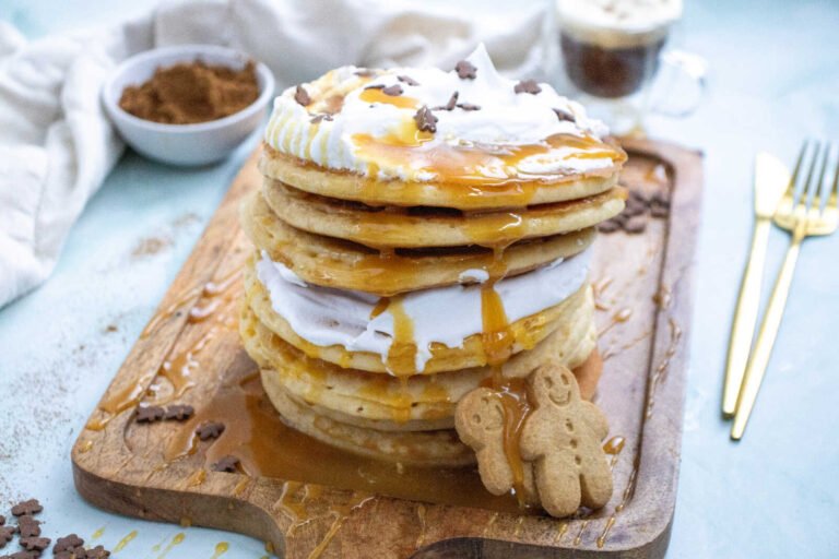 Gingerbread pancakes stack with whipped cream and maple syrup drizzle