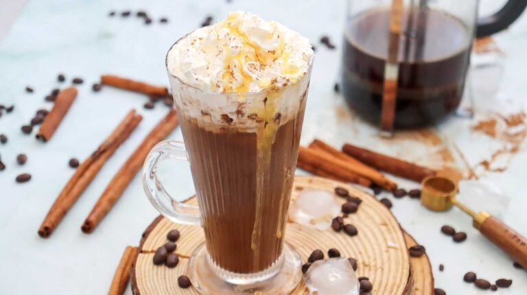 Starbucks iced cinnamon dolce latte copycat recipe with whipped cream, cinnamon, and caramel drizzle in a glass mug.